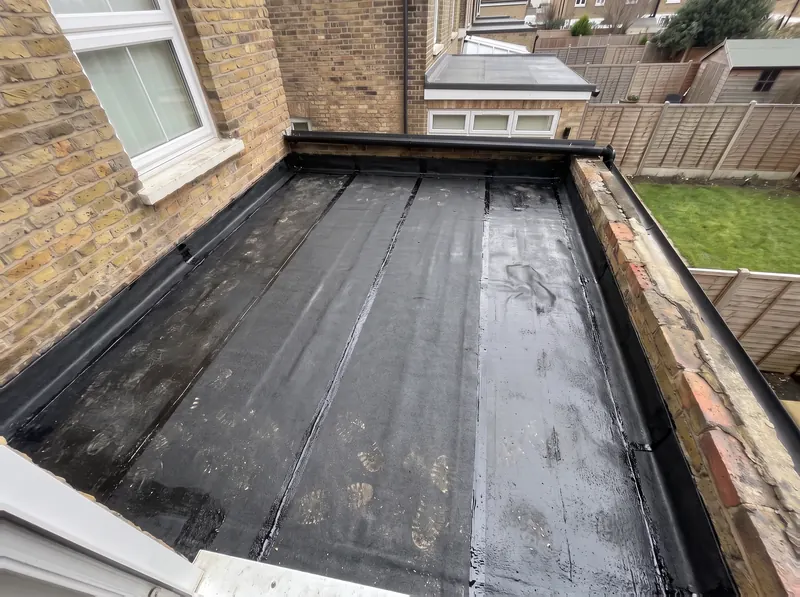 The same flat roof with a black torch-on base layer sealed over the new deck