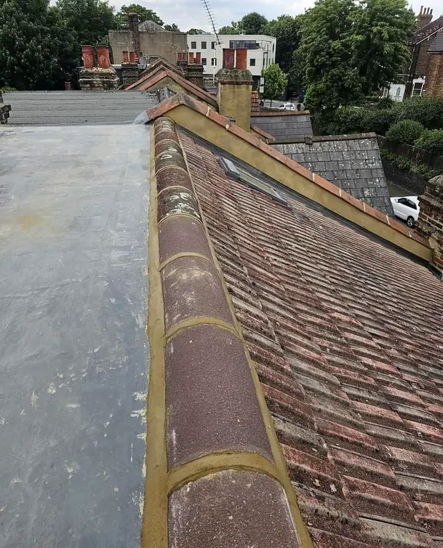 A new ridge bedded along the top of a re-tiled roof
