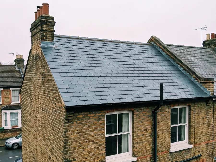 Illustration: the same roof re-slated in natural slate, with a new ridge, lead flashing and a clear gutter